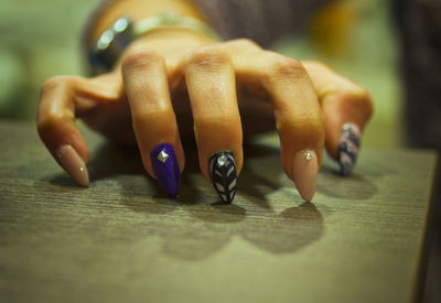Close-up of woman with painted nails on table