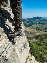 Low section of man standing on cliff against sky