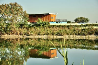 House by lake and building against sky
