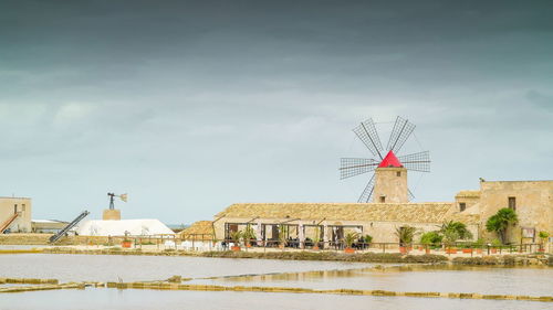 Traditional windmill by building against sky