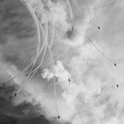 Low angle view of birds flying against cloudy sky