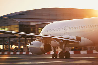 Airplane at busy airport. passenger plane on the move against terminal building at sunrise.