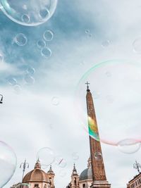 Low angle view of bubbles and buildings against sky