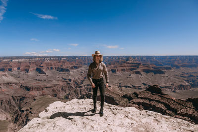 Man standing on rock against sky