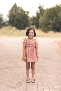 Laughing cute happy child girl 4-5 year old wearing trendy dress walking in park outdoors.