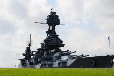 Battleship on field against sky