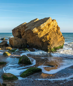 Rocks on shore by sea against sky