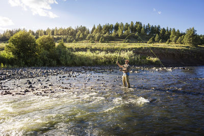 Man fishing in river on sunny day