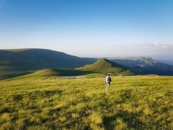 Rear view of man riding on grassy field against sky