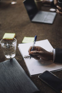 Hand of businessman holding pen by laptop and smart phone in office