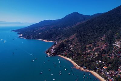 High angle view of sea and mountains against blue sky