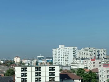 Buildings in city against clear blue sky