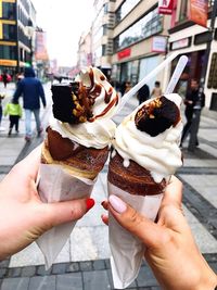 Cropped image of hand holding ice cream in city