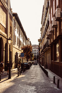 Empty road amidst buildings in city against sky