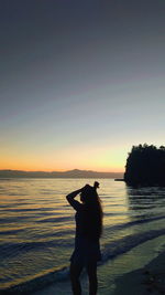 Silhouette man standing on beach against sky during sunset