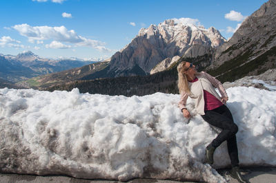 Woman standing on snowcapped mountain against sky