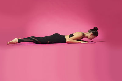 Woman lying on pink background