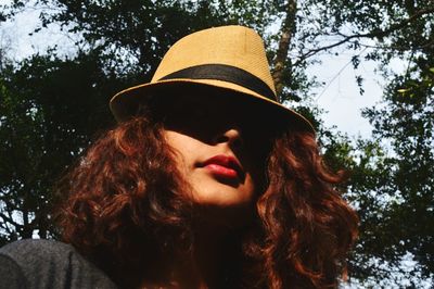Close-up of young woman wearing hat against trees