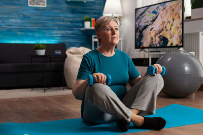 Full length of man sitting on floor at home