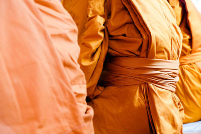 Midsection of monks wearing traditional clothing while sitting in temple