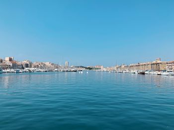 Scenic view of sea by buildings against clear blue sky