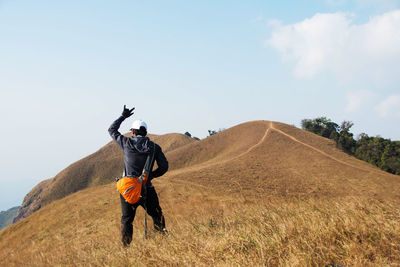 Rear view of hiker standing on mountain against sky