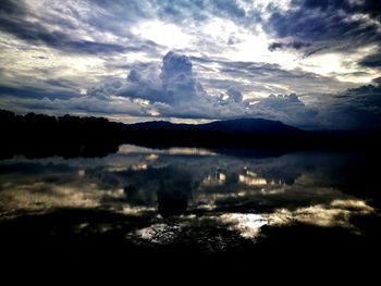 Scenic view of lake against cloudy sky during sunset