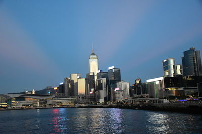 Sea by buildings against clear sky