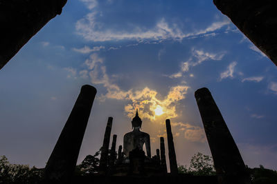Low angle view of silhouette buddha statue against blue sky during sunset