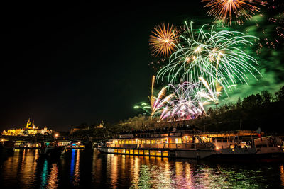 Firework display over river against sky at night