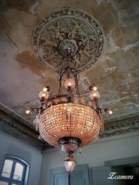 Low angle view of illuminated chandelier hanging on ceiling