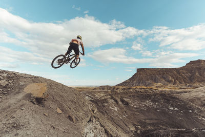 Male jumping with mountain bike in front of dramatic mountains