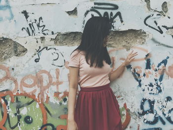 Close-up of woman standing against graffiti wall