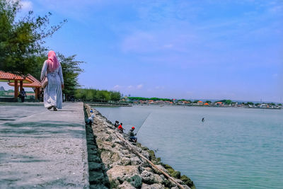 Rear view of people by sea against sky