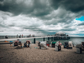 People on beach against cloudy sky