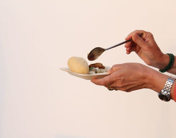 Midsection of person holding ice cream against white background