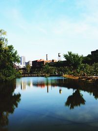 Reflection of trees and buildings in lake against sky