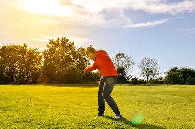 Man playing golf on course against sky during sunny day