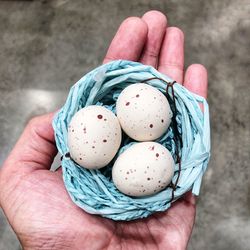 Close up with easter eggs in a basket on hand holding eggs. 