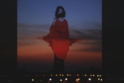 Woman standing against sky during sunset