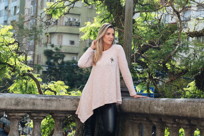 Woman looking away while standing by retaining wall