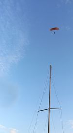 Low angle view of person paragliding against blue sky