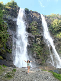 Rear view of woman standing against waterfall