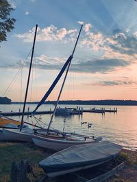 Sailboats moored in marina at sunset