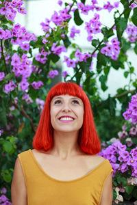 Smiling woman standing against pink flowering plants