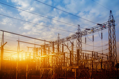 Low angle view of electricity pylon against sky during sunset