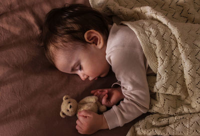 The kid sleeps sweetly with the teddy bear