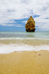 Rocks on beach by sea against sky