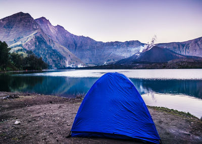 Tent on mountain by lake against sky