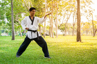 Full length of man practicing martial arts while standing in park
